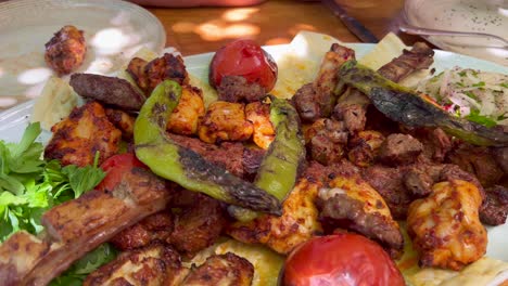 Eating-a-traditional-Turkish-big-meat-platter-mixed-grill-with-vegetables-and-fresh-pide-ekmek-bread-in-Bodrum-Turkey,-authentic-tasty-food,-4K-shot