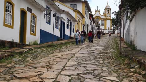 tourists-walking-down-cobblestone-slopes-of-historic-city-Tiradentes,-in-Minas-Gerais,-Brazil