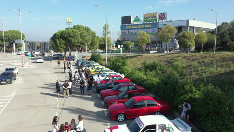 Aerial-view-over-row-of-parked-BMW-series-e30-classic-cars-at-fan-meeting-under-McDonalds-signage