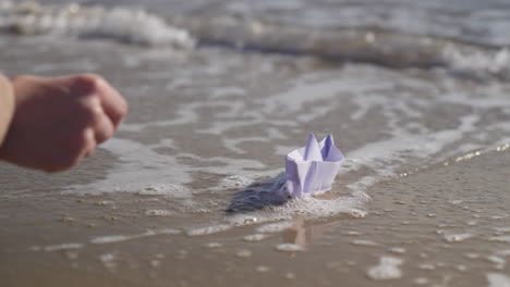 Die-Hand-Der-Frau,-Die-Origami-Boot-Im-Meer-Platziert