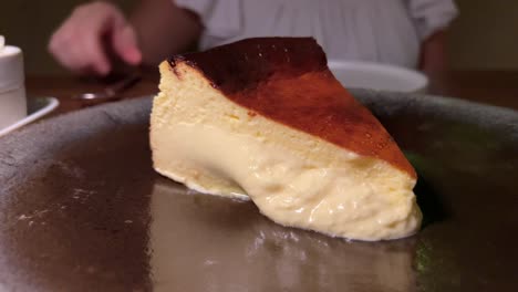 Traditional-Spanish-burnt-basque-cheesecake,-creamy-sweet-dessert-on-a-plate-in-a-restaurant,-4K-shot
