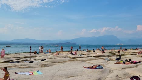 Touristen,-Die-Die-Sonne-Am-Strand-Von-Sirmione,-Italien,-Genießen