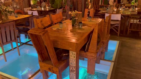 Beautiful-ocean-themed-restaurant-Boat-House-in-Ibiza-Spain,-cool-water-under-dining-table-design,-sea-fishing-decorations,-4K-shot