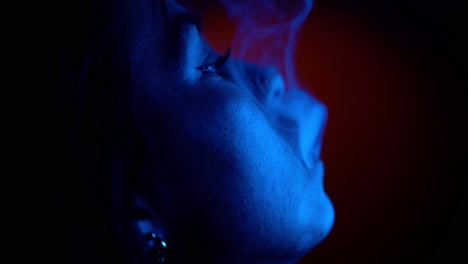 Close-up-shot-of-smoking-and-enjoying-smoke-in-studio-lighting-by-blue-light