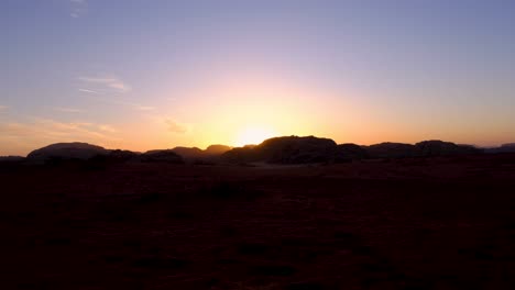 Time-lapse-of-sunset-with-last-rays-of-light-dipping-behind-rugged-mountains-in-vast,-remote-Wadi-Rum-desert-of-Jordan,-Middle-East