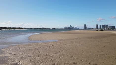 Fast-revealing-view-of-a-natural-sand-island-with-a-city-skyline-in-the-distance