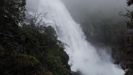 Tilt-down-shot-of-mystic-waterfall-crashing-down-in-rainforest,-slow-motion