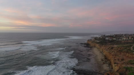 A-stunning-drone-shot-of-the-coast,-starting-above-the-cliffs-and-panning-up-along-the-shoreline,-capturing-the-crashing-waves-and-natural-beauty-of-the-seascape