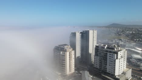 Layer-of-fog-coming-in-to-the-coastal-city-from-the-ocean-in-Bloubergstrand,-Cape-Town