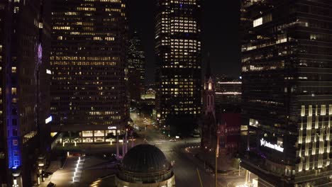 Drone-shot-soaring-through-downtown-Dallas,-Texas-at-night