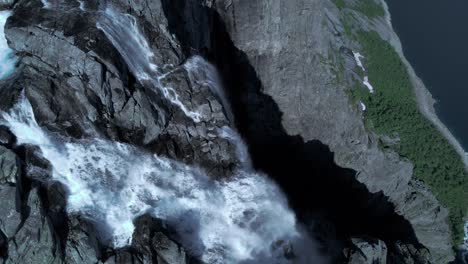 Aerial-top-down-shot-of-massive-water-flowing-down-waterfall-Trolltunga-in-Norway---Forest-woodland-in-the-valley