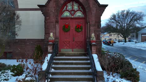 Slow-push-in-on-church-door-decorated-with-Christmas-wreaths