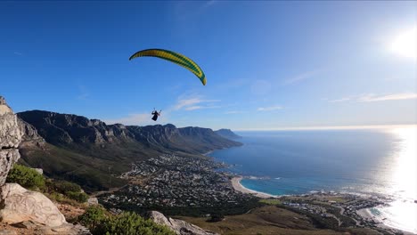 slow-motion-footage-of-a-paraglider-flying-towards-a-big-wall-of-cliffs-and-blue-ocean-in-the-background