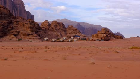 Tiendas-Beduinas-árabes-Anidadas-Contra-Las-Escarpadas-Montañas-En-El-Remoto-Desierto-De-Wadi-Rum,-Jordania,-Oriente-Medio