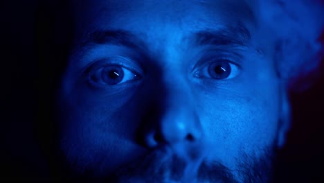 Makro-Nahaufnahme-Einer-Männlichen-Person,-Die-Durch-Blaues-Licht-Beleuchtet-Wird,-Das-Im-Professionellen-Studio-Eine-Zigarette-Raucht---Porträtaufnahme
