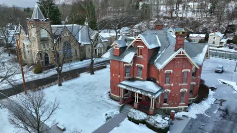Slow-aerial-of-Victorian-house-and-church-during-snow-storm