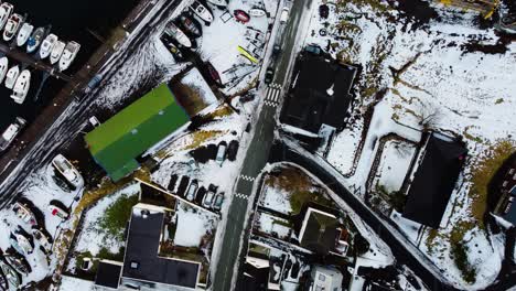 Drone-shot-overlooking-village-with-harbour-covered-in-snow-in-the-Faroe-Islands
