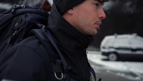 Man-in-a-black-jacket-and-a-cap-walking-in-the-streets-of-hallstatt-in-austria-in-winter,-december
