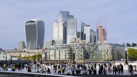 People-walking-with-view-of-city-Of-London-skyscrapers-and-modern-office-buildings-on-a-sunny-day-with-clear-skies