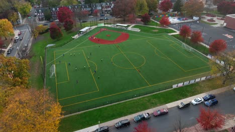 Aerial-orbit-around-soccer-team-practicing-on-multi-use-field-in-America-during-autumn