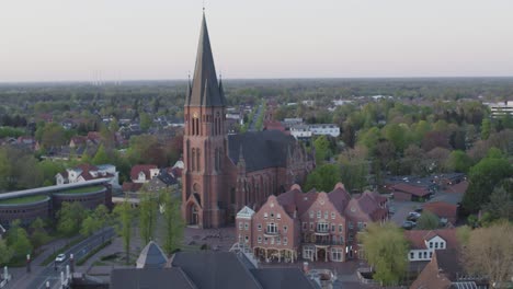 Kirche-Mitten-In-Einer-Stadt-Im-Norden-Deutschlands-Während-Des-Drohnenflugs-Bei-Sonnenuntergang
