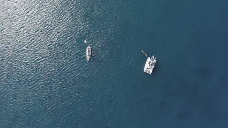 An-aerial-birds-eye-view-of-two-sailboats-in-the-sea-with-the-sun-at-midday