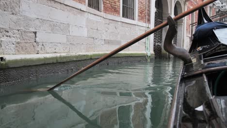 Dreamy-slow-motion-paddle-dips-into-tranquil-canal-from-a-gondola-in-Venice,-Italy