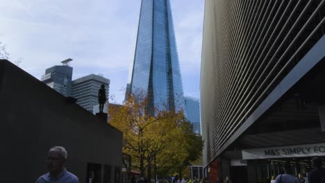 People-walk-as-Shard-tower-is-seen-from-below-at-London-Bridge-City,-south-west-of-Tower-Bridge-in-London