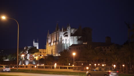 Zu-Fuß-Entlang-Der-Belebten-Straße-Mit-Blick-Auf-Die-Kathedrale-Basilika-Von-Santa-Maria-De-Mallorca,-Die-Nachts-Beleuchtet-Wird