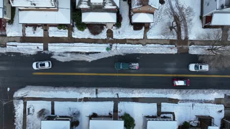 Top-down-aerial-of-cars-driving-on-snowy-streets-in-winter
