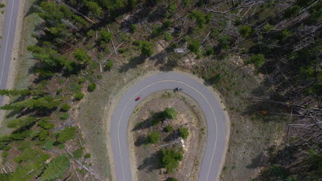 Rising-aerial-shot-of-cyclists-biking-through-winding-roads-in-Colorado