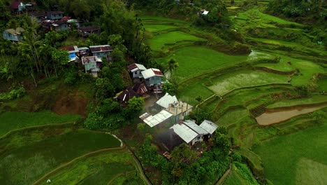Over-head-shot-of-Phillippine-houses-and-huts-surrounded-by-rice-paddy-fields-in-the-hillside