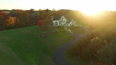 Aerial-of-large-modern-American-home-in-rural-countryside-at-autumn-sunset