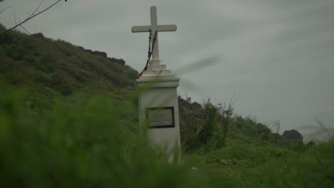 white-ancient-tombstone-in-shape-of-a-cross-in-a-forest-near-the-beach-under-grey-sky
