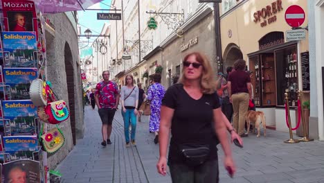Shoppers-and-tourists-walking-along-Getreidegasse,-main-shopping-street,-in-Salzburg,-Austria