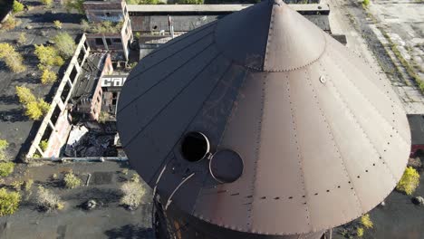 Open-water-tower-lid-of-Packard-Plant-in-Detroit,-aerial-fly-away-view