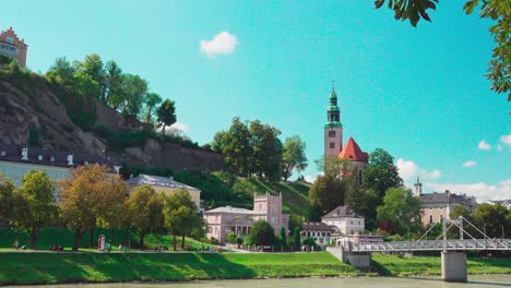 Vista-Desde-Elisabethkai-Hacia-La-Pasarela-Müllnersteg-Y-La-Iglesia-Müllner-En-Salzburgo,-Austria
