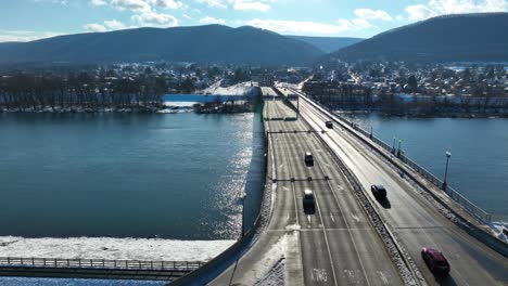 Aerial-truck-shot-of-cars-driving-on-bridge-over-icy-Susquehanna-river-in-Williamsport-PA