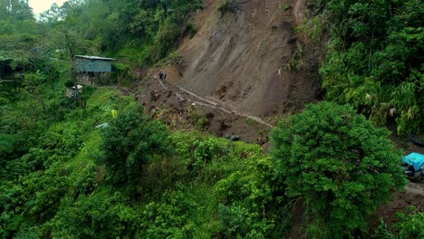 Landslide-over-a-narrow-dirt-road-in-the-green-Phillippine-mountains-with-people-and-vehicles-stuck
