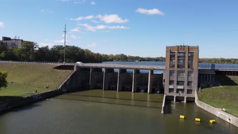 Cars-driving-over-Ypsilanti-water-dam-on-sunny-day,-aerial-drone-view