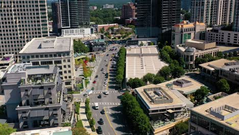 Aerial-drone-shot-slowly-panning-down-looking-over-the-main-street-in-downtown-Buckhead-in-Atlanta,-GA