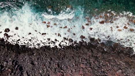 Aerial-top-down-view-of-black-volcanic-beach-with-turquoise-ocean-waves
