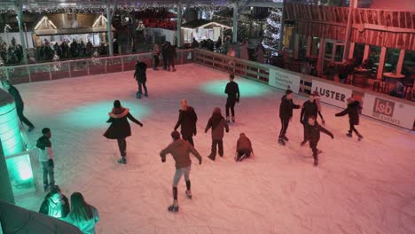 top-view-of-people-ice-stating,-kids-playing-on-ice-at-Christmas-market-in-Maastricht-in-The-Netherlands