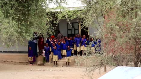 Afrikanische-Schulkinder-Mit-Blauen-Uniformen-Winken-Zum-Abschied,-Tansania