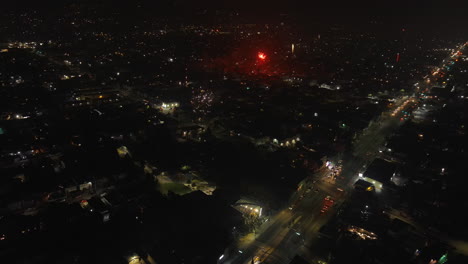 Aerial-view-of-fireworks-above-residential-neighborhood-at-night