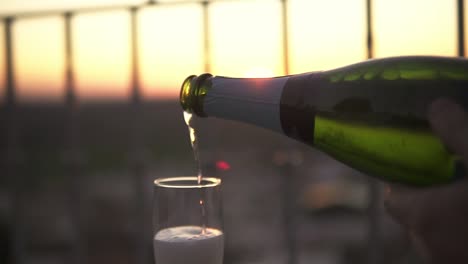 Slowmotion-shot-of-a-bottle-of-prosecco-being-poured-into-a-glass-at-sunset