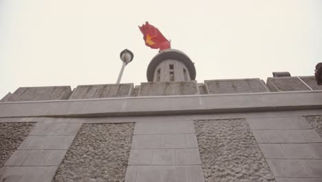 looking-up-to-Lũng-Cú-Flag-Tower-behind-wall-with-Vietnamese-flag-fluttering-in-the-wind