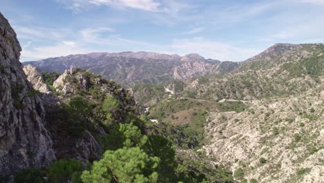 Low-level-aerial-view-revealing-high-mountain-peaks-and-Mediterranean-forest