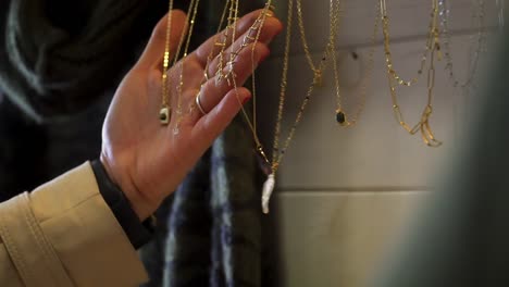 Slowmotion-close-up-shot-of-a-woman-browsing-the-gold-jewelry-on-sale-in-a-shop