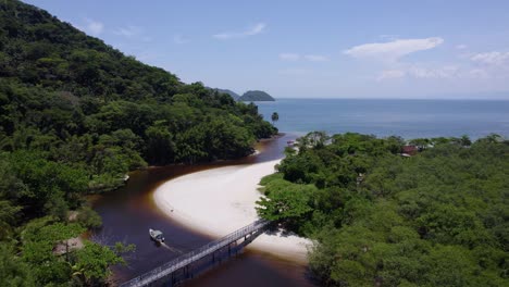 Aerial-view-of-a-boat-driving-in-the-Rio-Sahy-river-towards-the-sea-in-sunny-Brazil